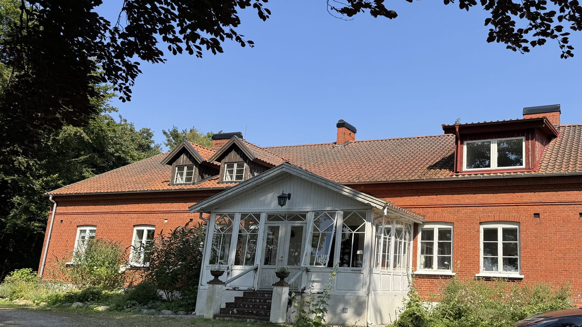 Sekelskiftesvilla i tegel med vita originalfönster och veranda — Sweacraft Stockholm